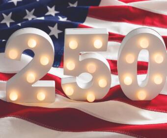 Lit marquee numbers 2 5 0 in front of an American flag backdrop.