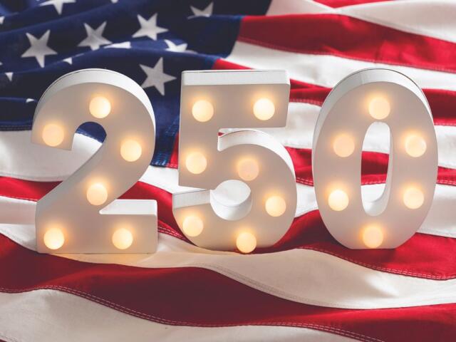 Lit marquee numbers 2 5 0 in front of an American flag backdrop.