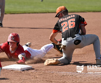 Baserunner slides into second base as a fielder reaches to tag him on a dusty infield pose