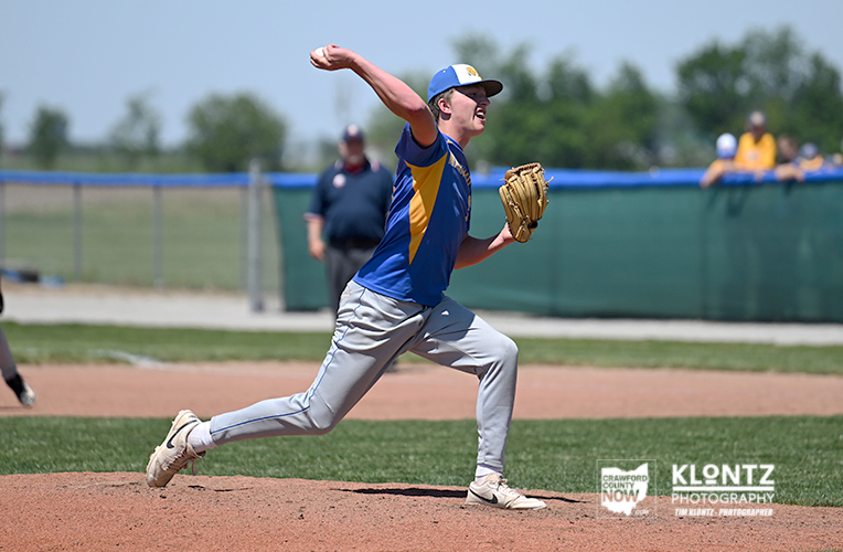 Baseball pitcher in blue and yellow uniform delivering a pitch on the mound.