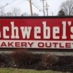 Schwebel's Bakery Outlet sign on a roadside with a red background and white lettering, outdoor scene
