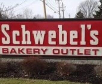 Schwebel's Bakery Outlet sign on a roadside with a red background and white lettering, outdoor scene