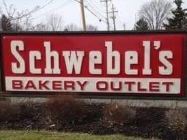 Schwebel's Bakery Outlet sign on a roadside with a red background and white lettering, outdoor scene