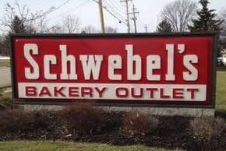 Schwebel's Bakery Outlet sign on a roadside with a red background and white lettering, outdoor scene
