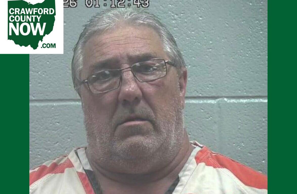 Mugshot of a middle-aged man with gray hair and glasses in orange-and-white jail clothes, against a gray wall; Crawford County Now logo in the corner.