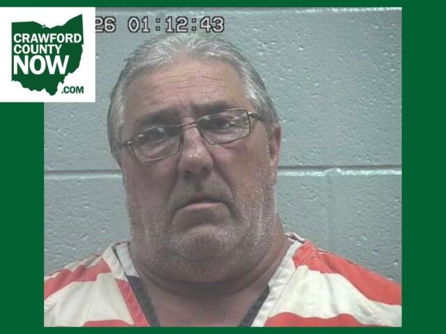 Mugshot of a middle-aged man with gray hair and glasses in orange-and-white jail clothes, against a gray wall; Crawford County Now logo in the corner.