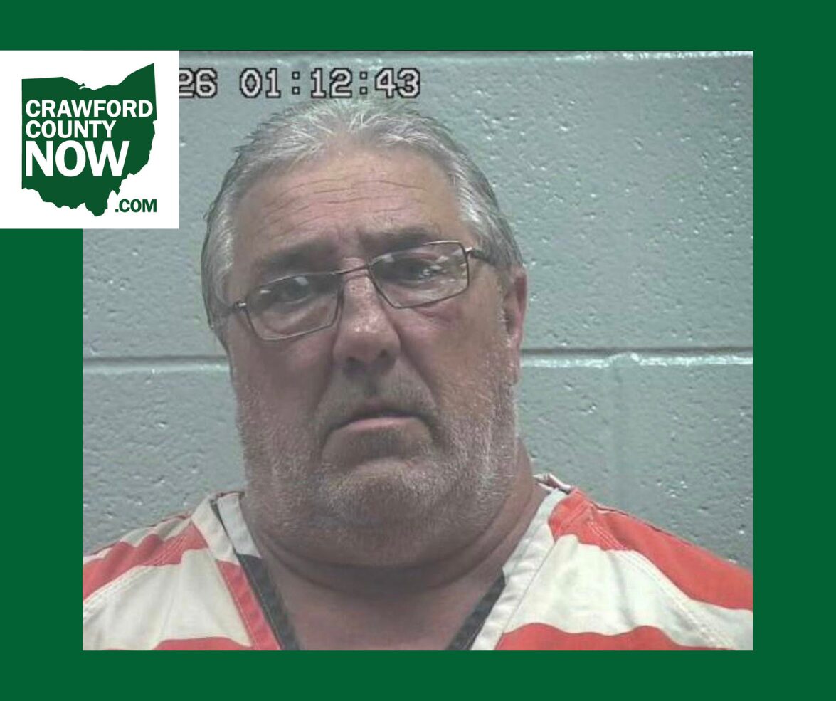 Mugshot of a middle-aged man with gray hair and glasses in orange-and-white jail clothes, against a gray wall; Crawford County Now logo in the corner.