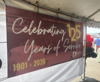 Banner reading 'Celebrating 125 Years of Service' for Ohio Mutual, 1901–2026, under a tent with red and black balloons nearby.
