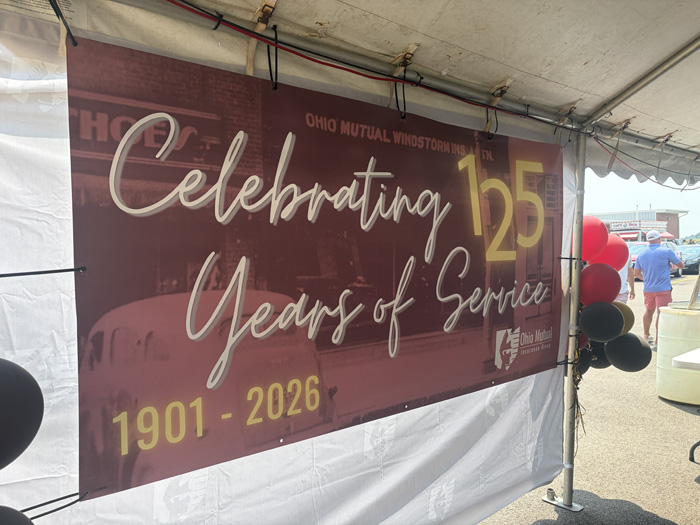 Banner reading 'Celebrating 125 Years of Service' for Ohio Mutual, 1901–2026, under a tent with red and black balloons nearby.