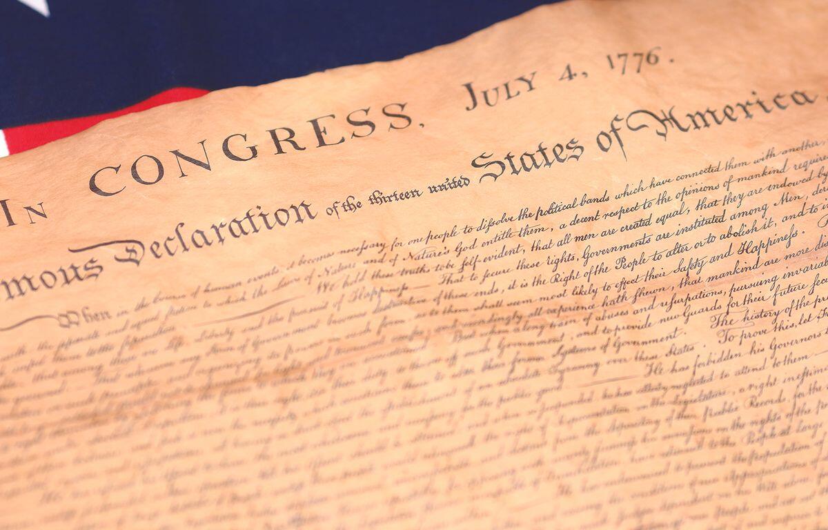Close-up of an aged parchment showing the title 'In Congress, July 4, 1776' and 'Declaration of the United States of America'—a historical document scene.