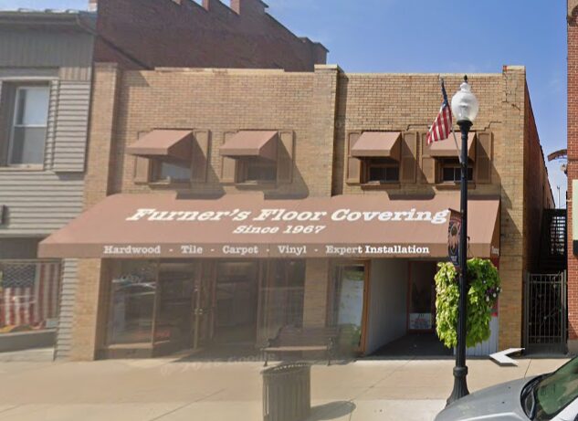 Storefront of Furner's Floor Covering, brick building with a brown awning and service text visible on it at street level