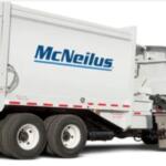 White McNeilus concrete mixer truck with a large rotating drum, viewed from the side.