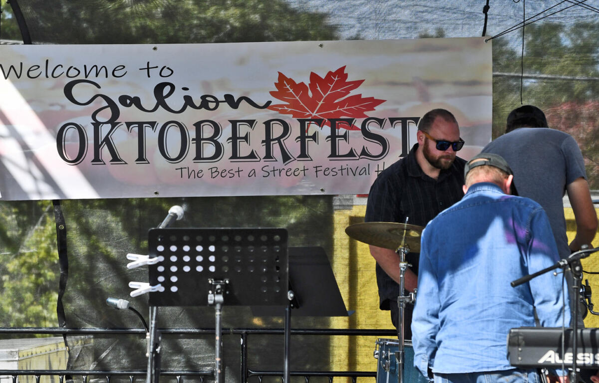 Stage at Galion Oktoberfest with a banner reading 'Welcome to Galion Oktoberfest' and a small band setup including a drummer and keyboard on the right side.