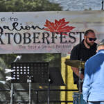 Stage at Galion Oktoberfest with a banner reading 'Welcome to Galion Oktoberfest' and a small band setup including a drummer and keyboard on the right side.