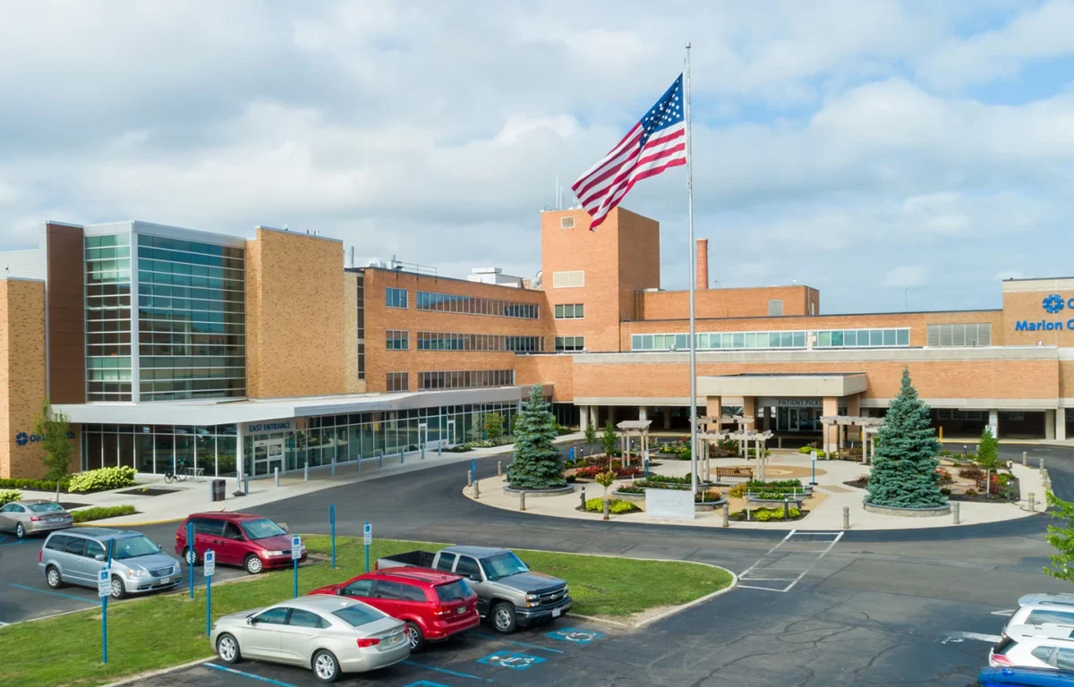 Exterior view of OhioHealth Marion General Hospital with a tall flagpole and a landscaped circular driveway in front.