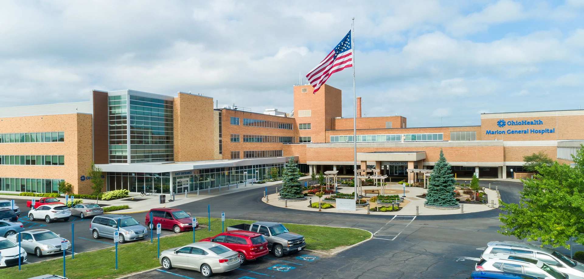 Exterior view of OhioHealth Marion General Hospital with a tall flagpole and a landscaped circular driveway in front.